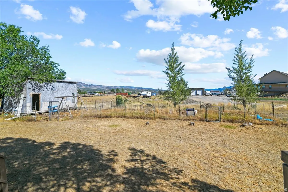 Expansive outdoor area featuring a shed, mature trees, and wire fencing