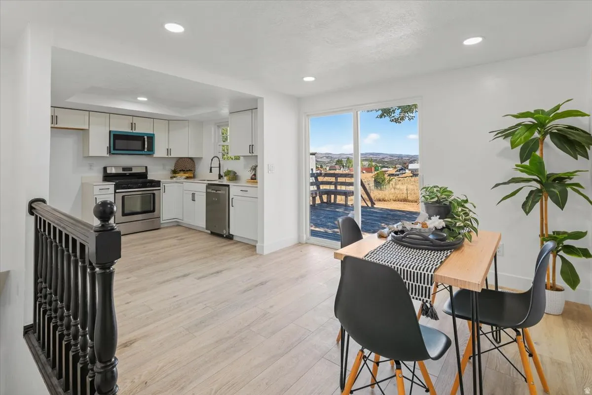 Light wood-finish flooring throughout, white upper and lower cabinetry, stainless steel appliances.