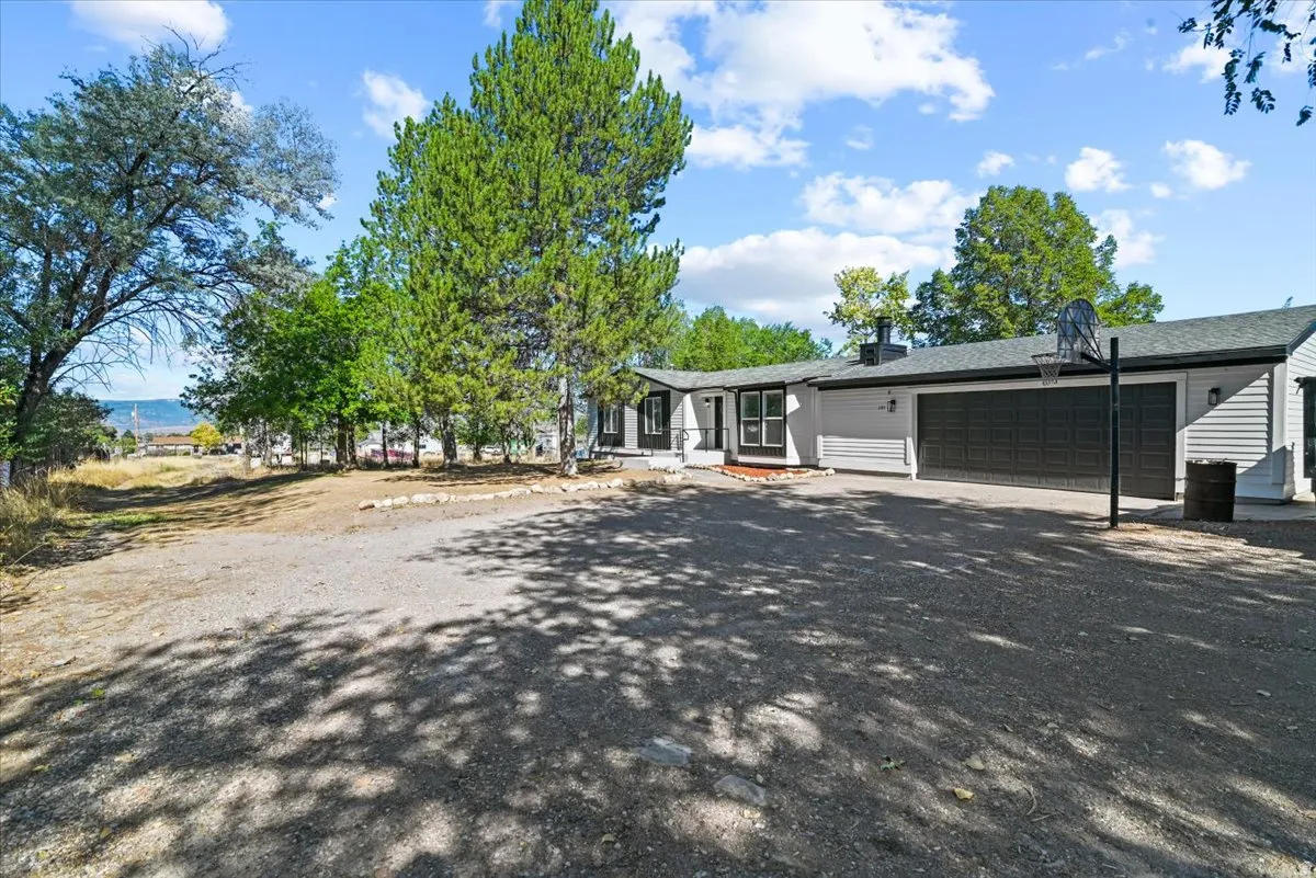 Ranch-style exterior with gray siding, black garage doors, and a dark roof