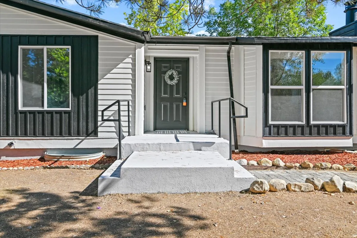 Exterior featuring horizontal siding, vertical paneling, a concrete entry with railings, and a bay window