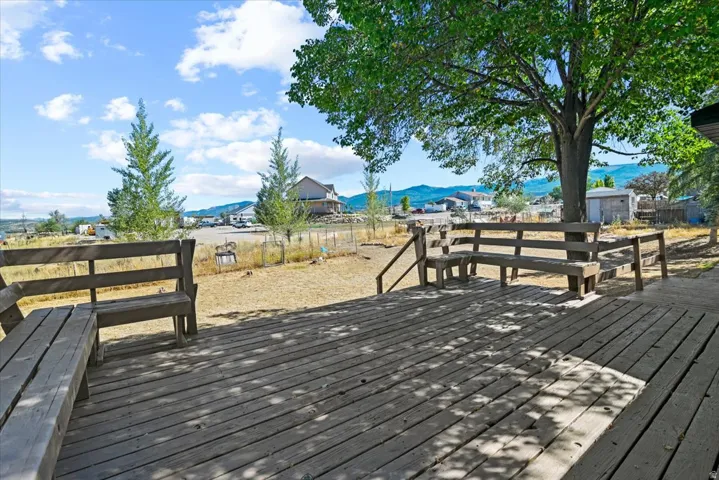Expansive outdoor wooden deck with integrated bench seating, framed by mature trees