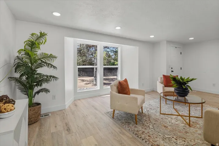 Recessed lighting, light wood-finish flooring, white walls, and a white paneled door