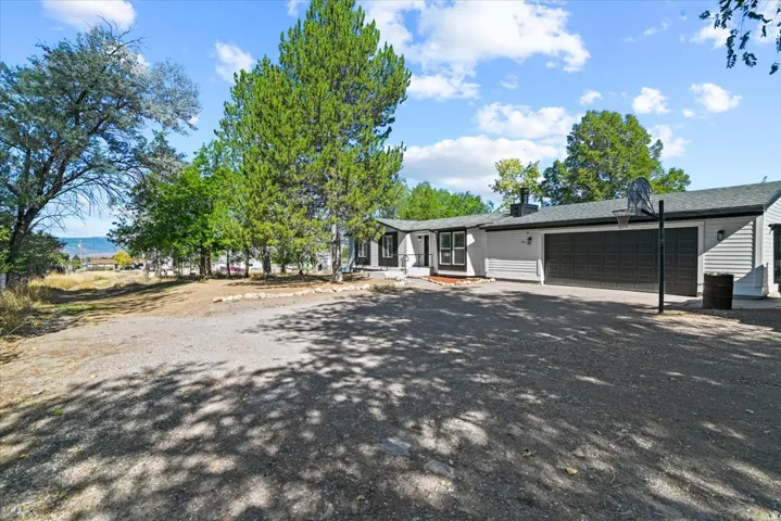 Ranch-style exterior with gray siding, black garage doors, and a dark roof