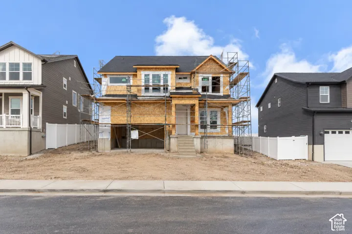 Two-story residential structure under construction featuring a shingle roof, multi-pane windows, and a concrete foundation
