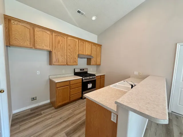Kitchen with wood-finish cabinetry, light-toned countertops, and a gas range