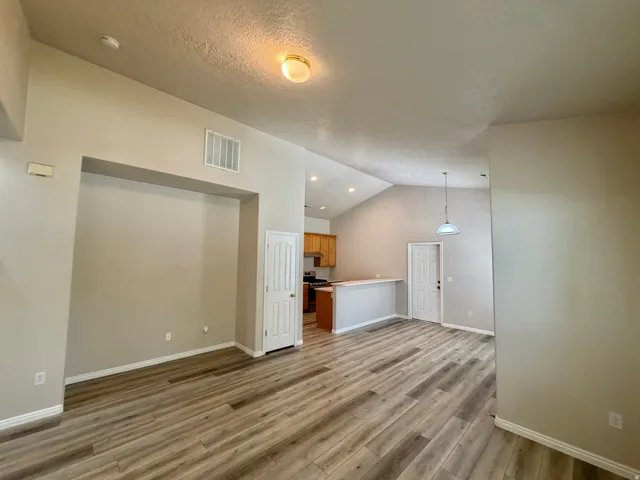 Vaulted ceiling with recessed lighting, wood-finish flooring, white paneled doors, and a breakfast bar