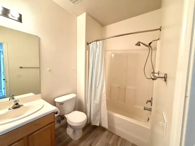 Bathroom featuring a single vanity with wood-finish cabinetry, a white countertop, and a built-in sink