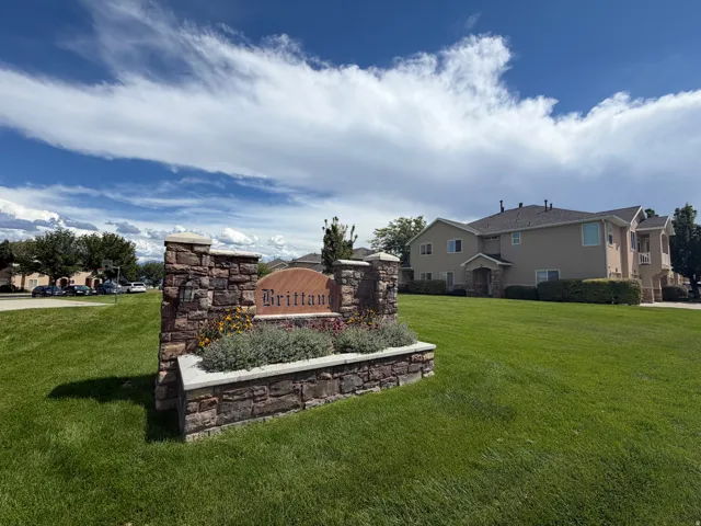 Stone-clad entry monument with integrated plantings, surrounded by expansive green spaces and multi-level residential structures