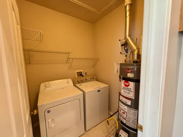 Utility closet with a water heater, laundry appliance hookups, and wire shelving
