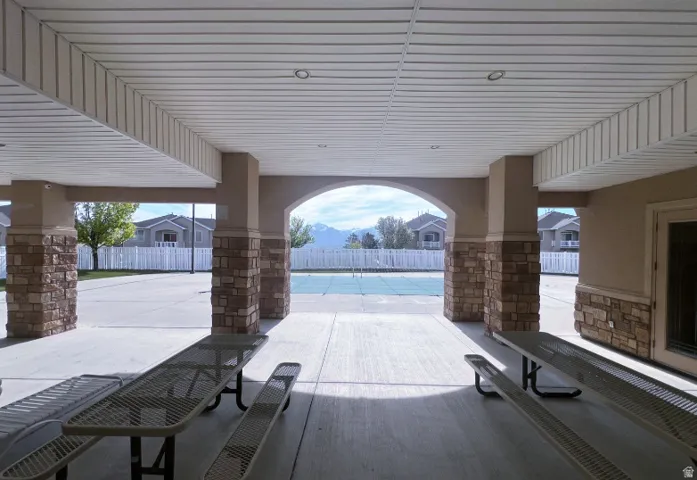 Covered patio structure featuring stone-clad pillars, arched openings, and a finished ceiling with recessed lighting