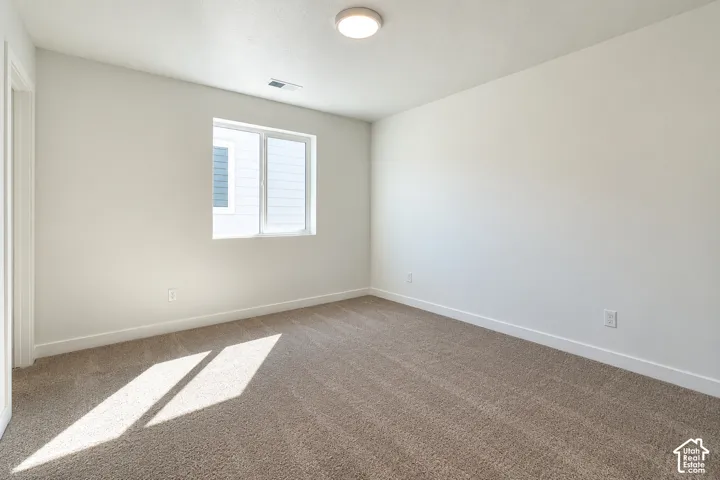 Neutral tone wall paint, carpeted flooring, window with white frame, white trim, and a ceiling-mounted light fixture