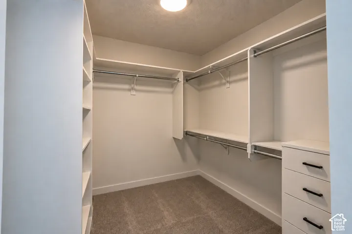 Built-in closet system featuring multiple hanging rods, integrated shelving, and drawer storage with dark hardware