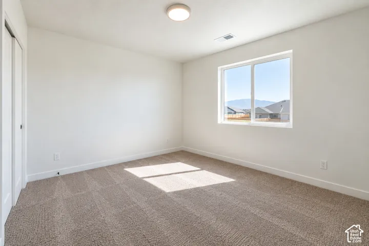Carpeted room featuring a large window, white walls, and a flush-mount ceiling light
