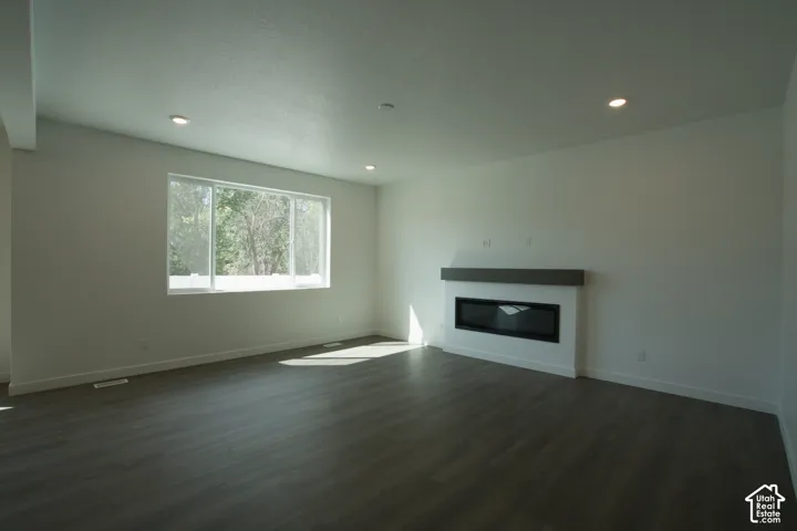 Recessed lighting, wood-finish flooring, large window, linear electric fireplace, and a wood mantle