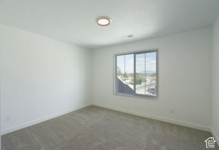 Neutral tone wall finishes, gray patterned carpeting, recessed ceiling fixture, and a large window