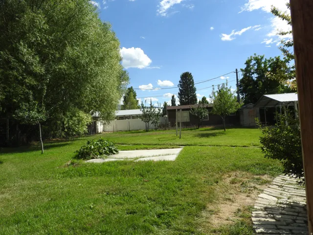 Expansive lawn area featuring mature trees and a concrete pad