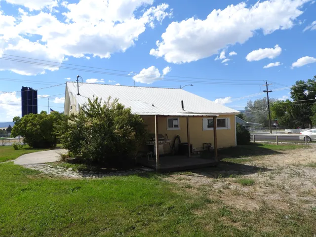 Yellow exterior with a white metal roof, featuring a covered wooden deck