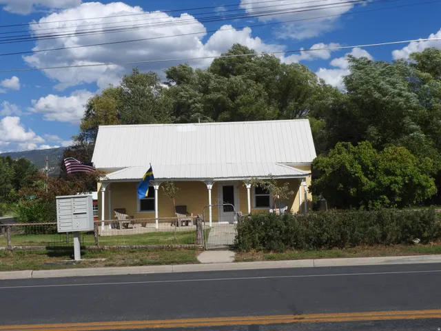Yellow exterior with white trim, metal roofing, and a covered front porch featuring decorative columns