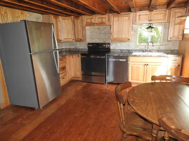Kitchen featuring wood-finish flooring, wood cabinetry, stone countertops, and stainless steel appliances