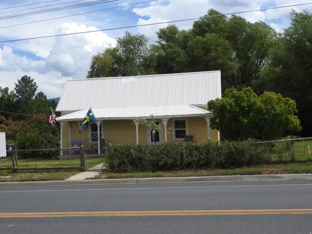 Yellow exterior with a white metal roof and a covered front porch featuring decorative columns