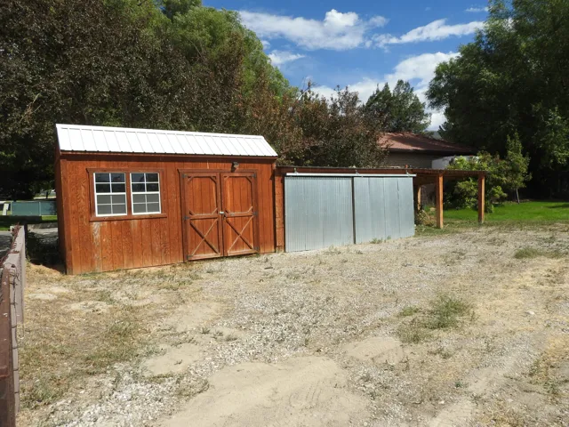 Wood-sided shed with a white metal roof and double doors