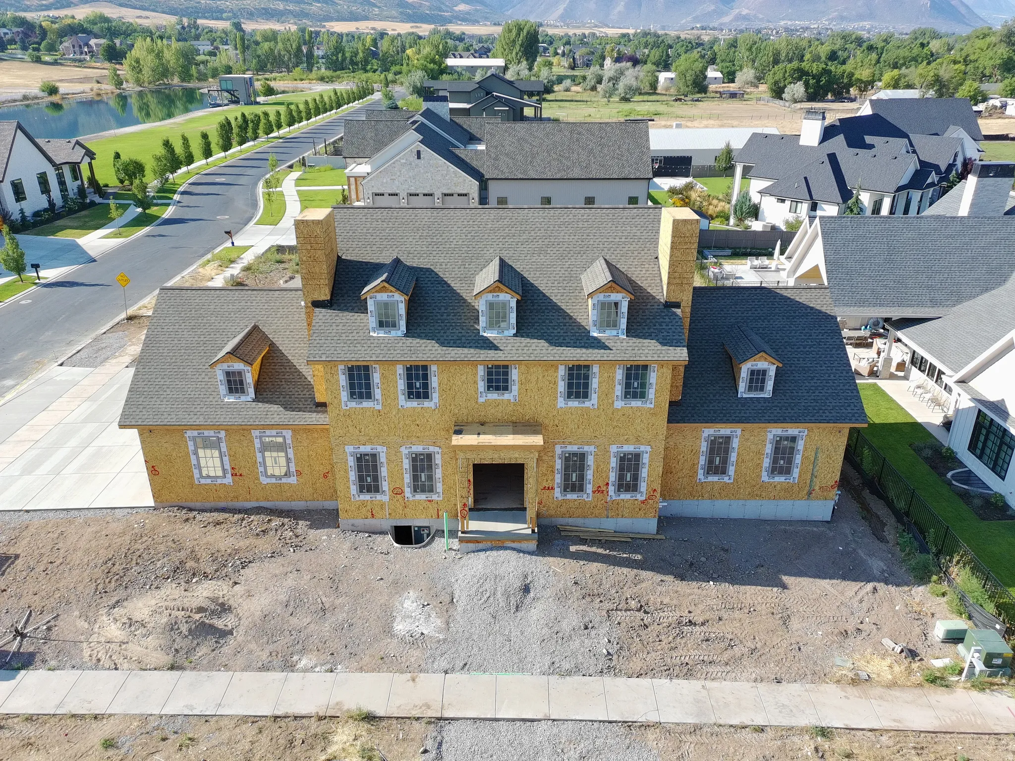New construction property featuring multiple dormer windows, a prominent front entrance, and a substantial roofline