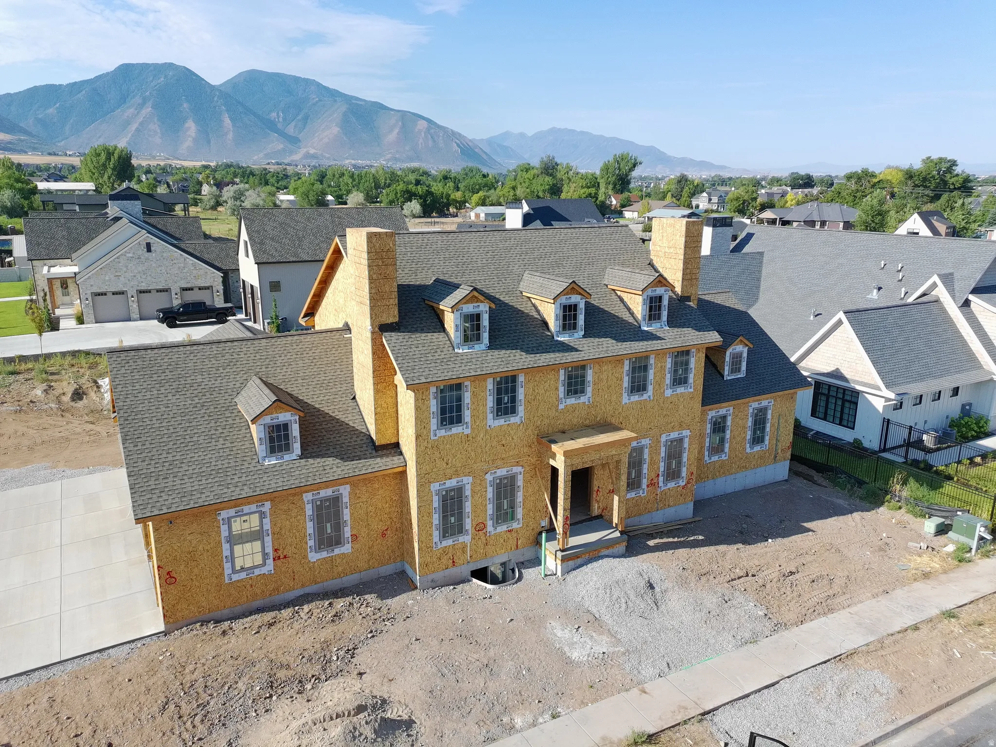 House under construction featuring multiple dormer windows, a prominent chimney, and a covered entry