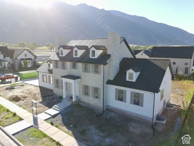 Stone exterior with white siding accents, dormer windows, and a prominent front entrance with a covered porch