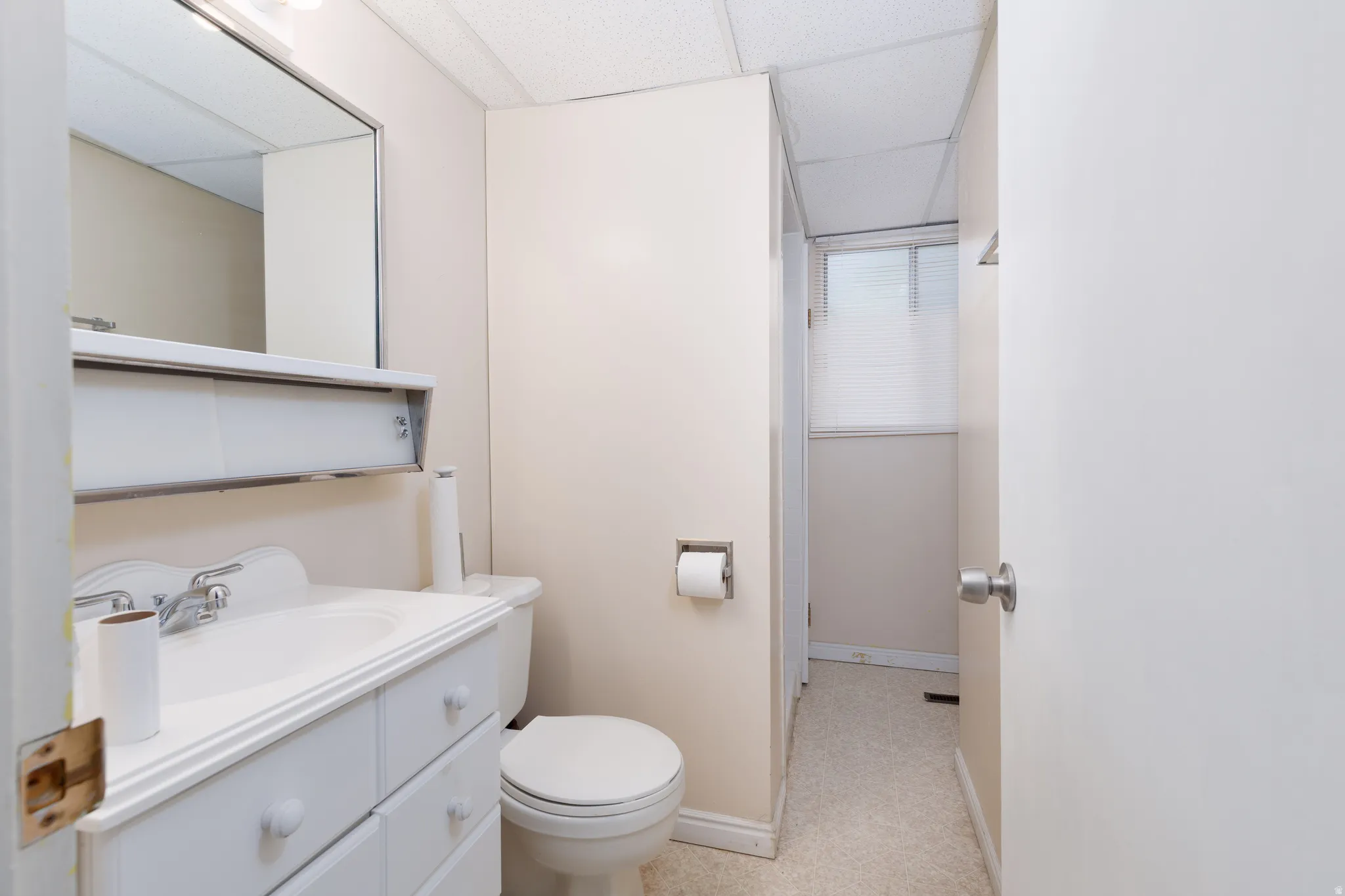 Bathroom featuring a vanity with integrated sink, chrome faucet, and a wall-mounted mirror