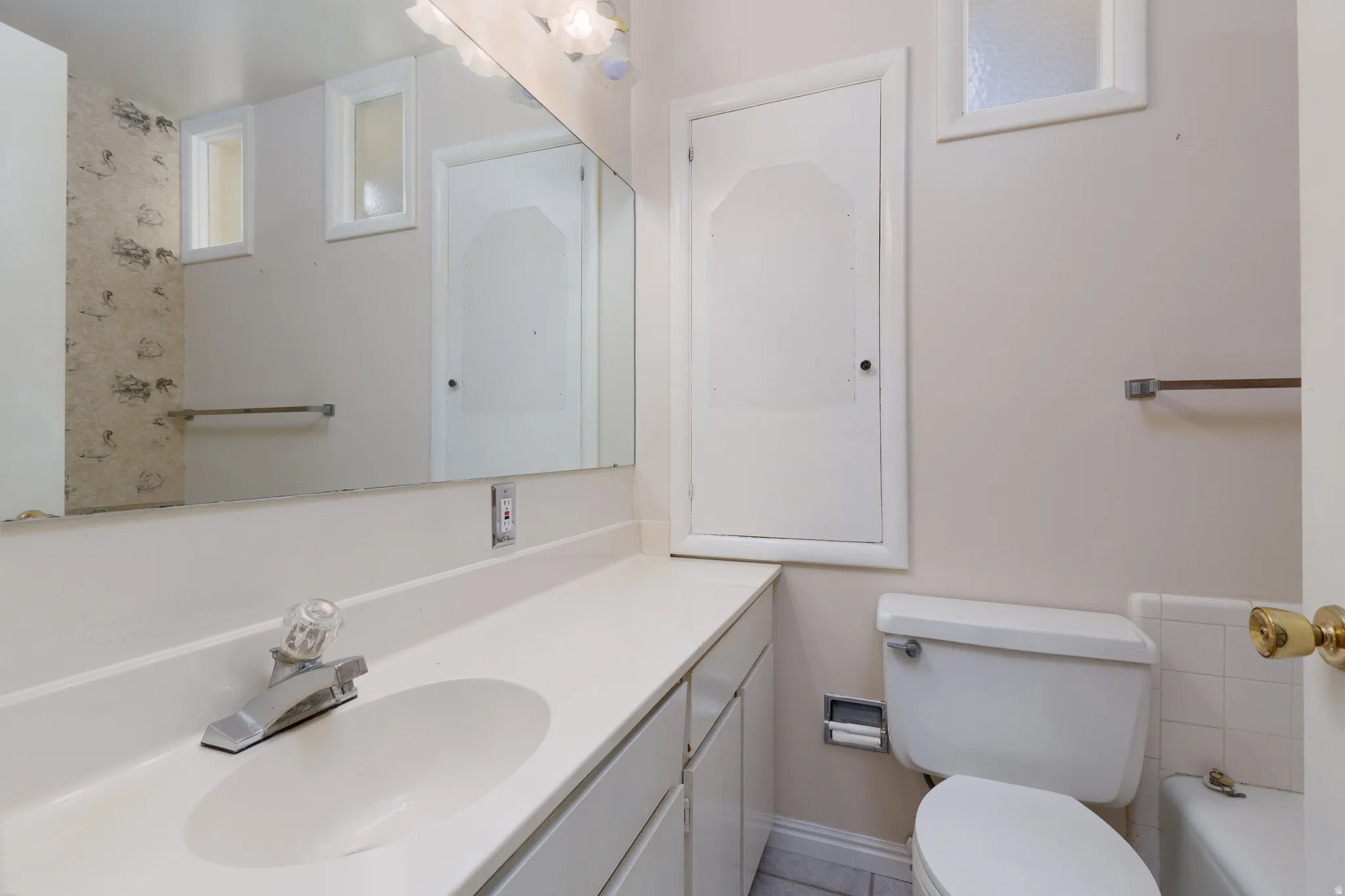 Bathroom vanity featuring a white countertop, integrated sink, and chrome faucet