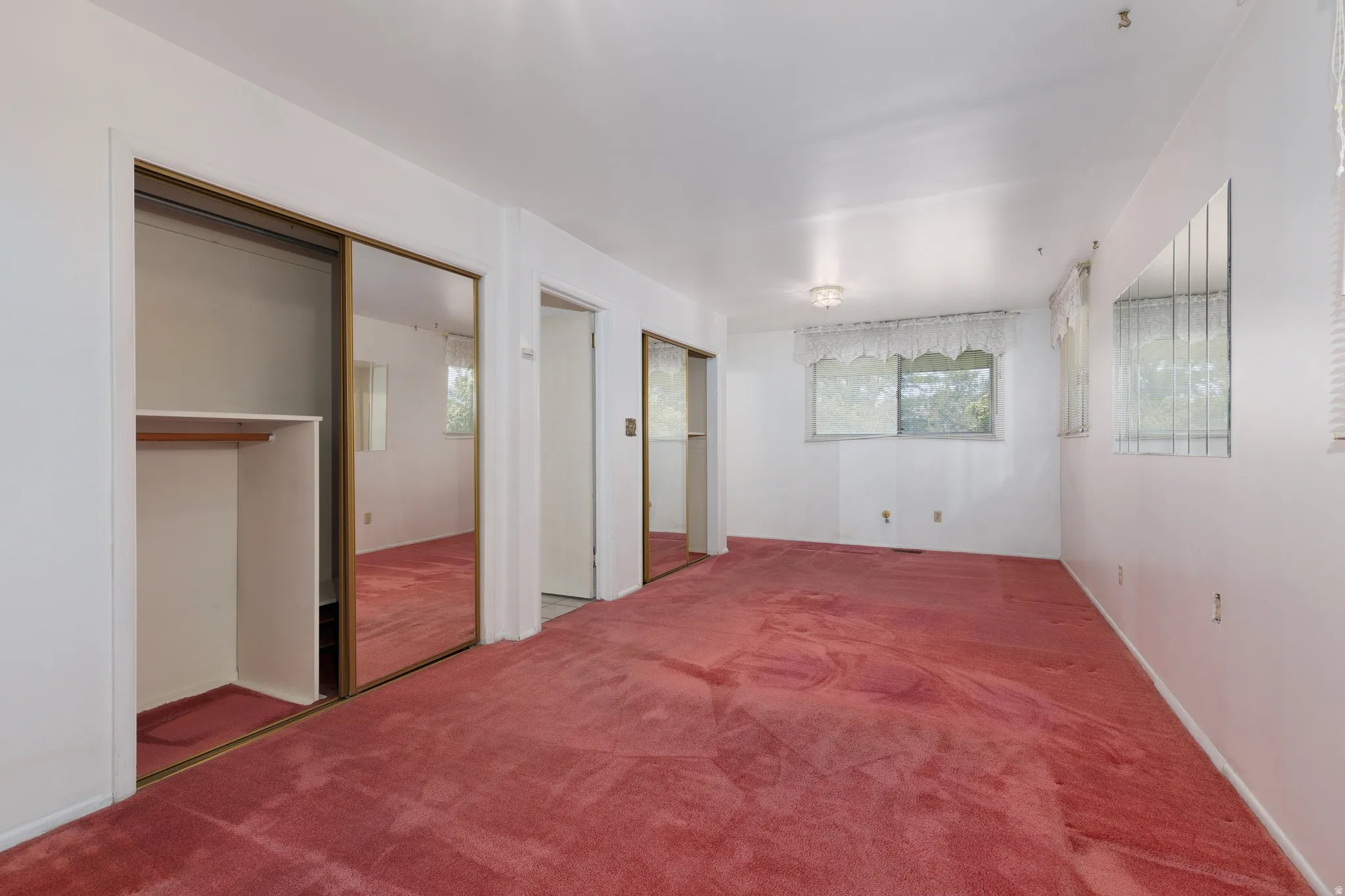 Expansive room featuring red carpeting, white walls, and multiple windows