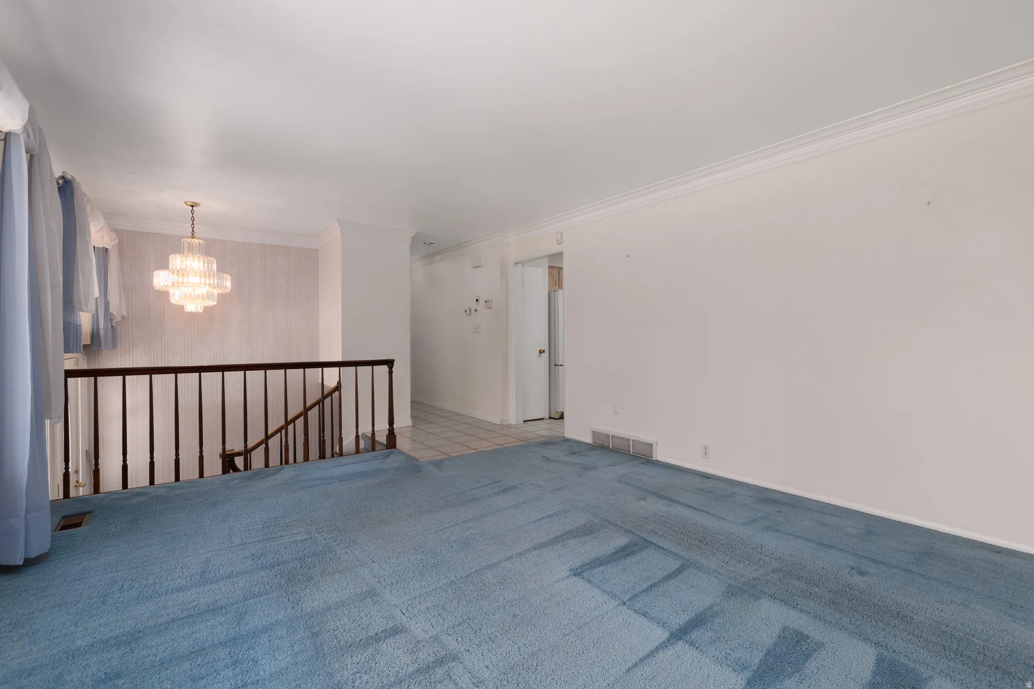 Carpeted living area with white walls and crown molding