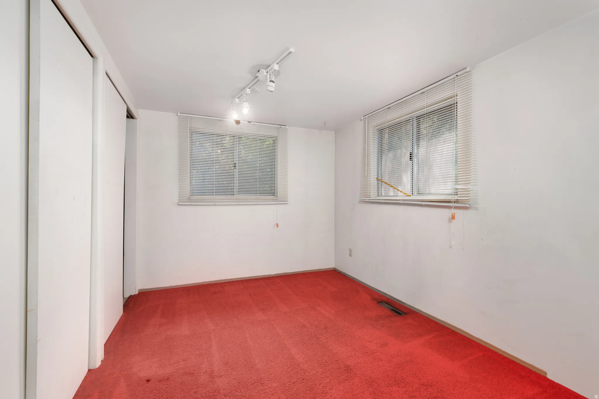 Room featuring dual windows, track lighting, and built-in closet with sliding doors