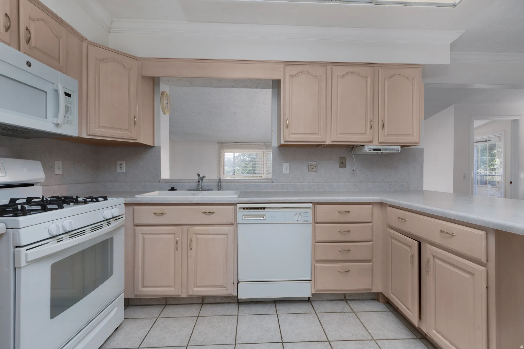 Kitchen featuring wood-finish cabinetry, white appliances, and a double basin sink