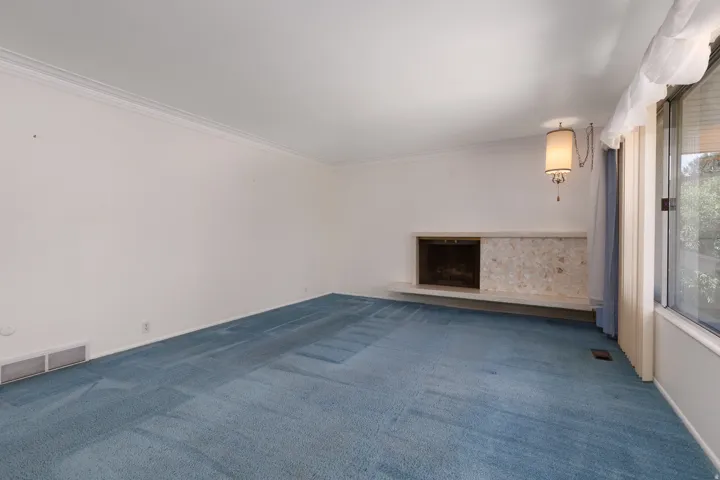 Living area with a stone-surround fireplace, an integrated hearth, a wall-mounted chandelier, crown molding, and large windows