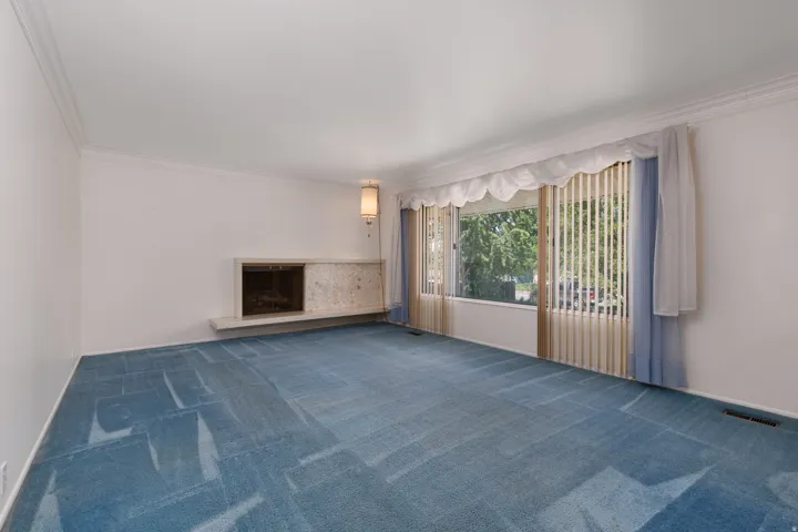 Bright living area featuring an expansive window, crown molding, and a built-in fireplace with a stone surround