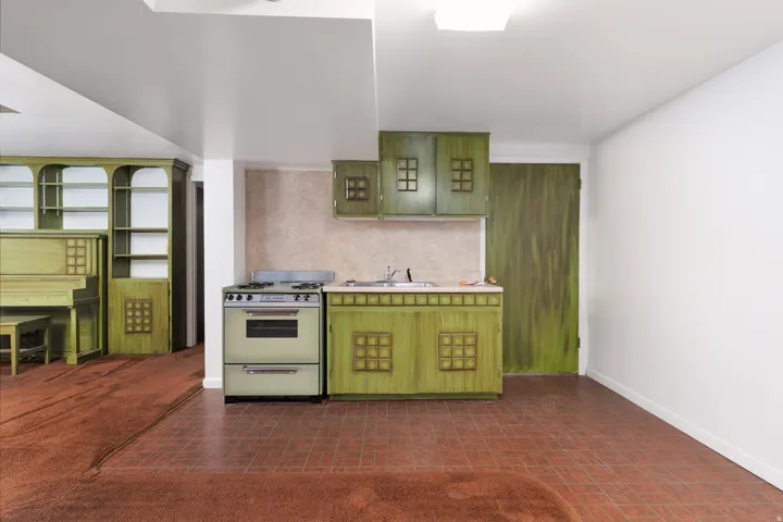 Compact kitchen area featuring green cabinetry, a single basin sink, a gas range, and a tiled backsplash