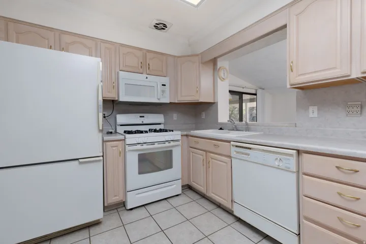 Kitchen featuring light-toned cabinetry and white appliances