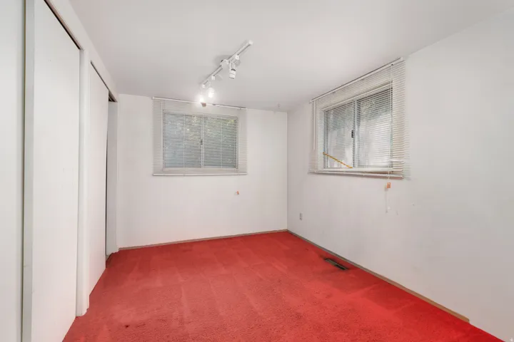 Room featuring dual windows, track lighting, and built-in closet with sliding doors
