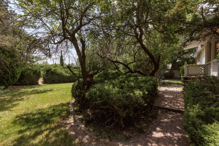 Mature landscaping featuring a brick pathway and manicured shrubs