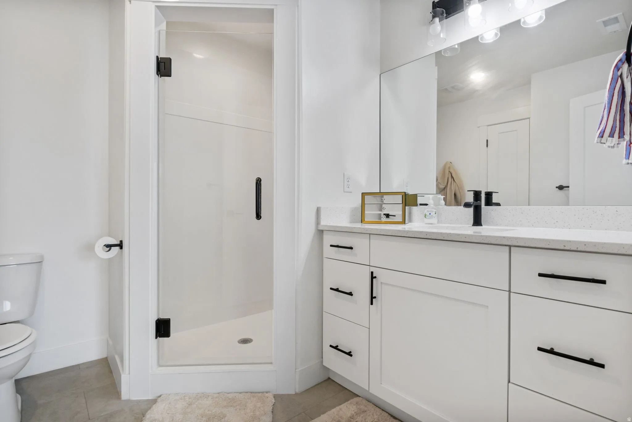 White vanity with a solid surface countertop, undermount sink, and matte black fixtures
