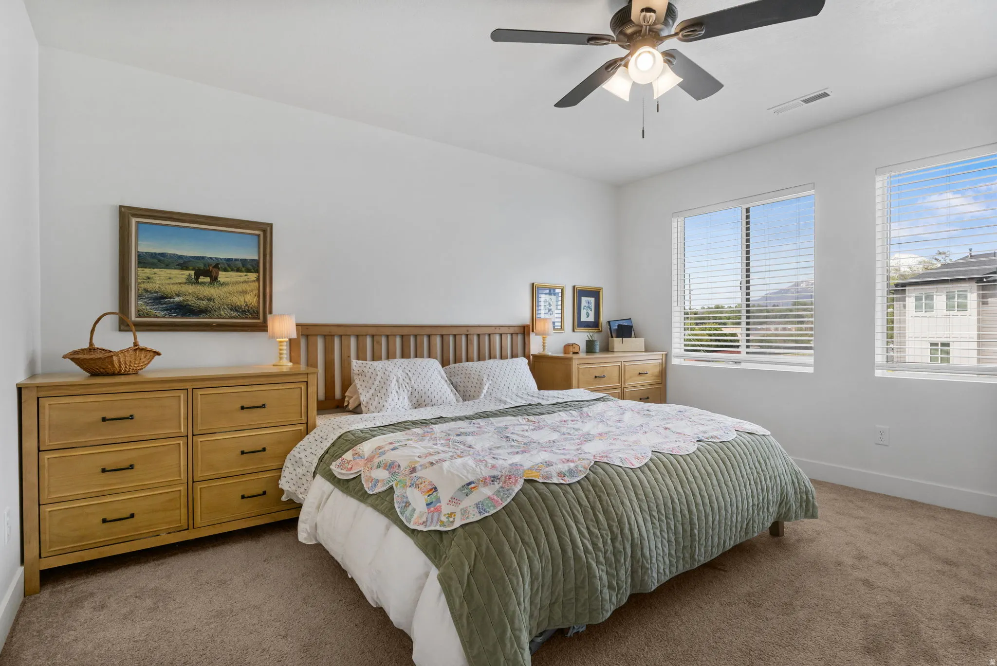 Dual windows featuring blinds, ceiling fan with light fixture, and neutral carpeting