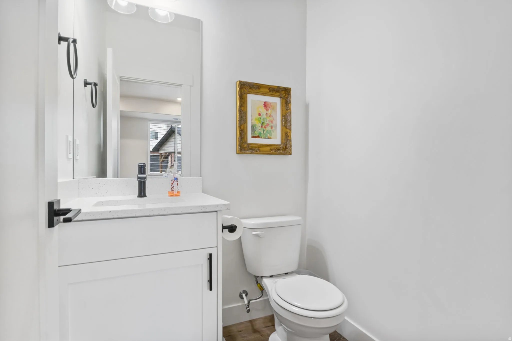White vanity with a speckled countertop, matte black faucet, and coordinating hardware