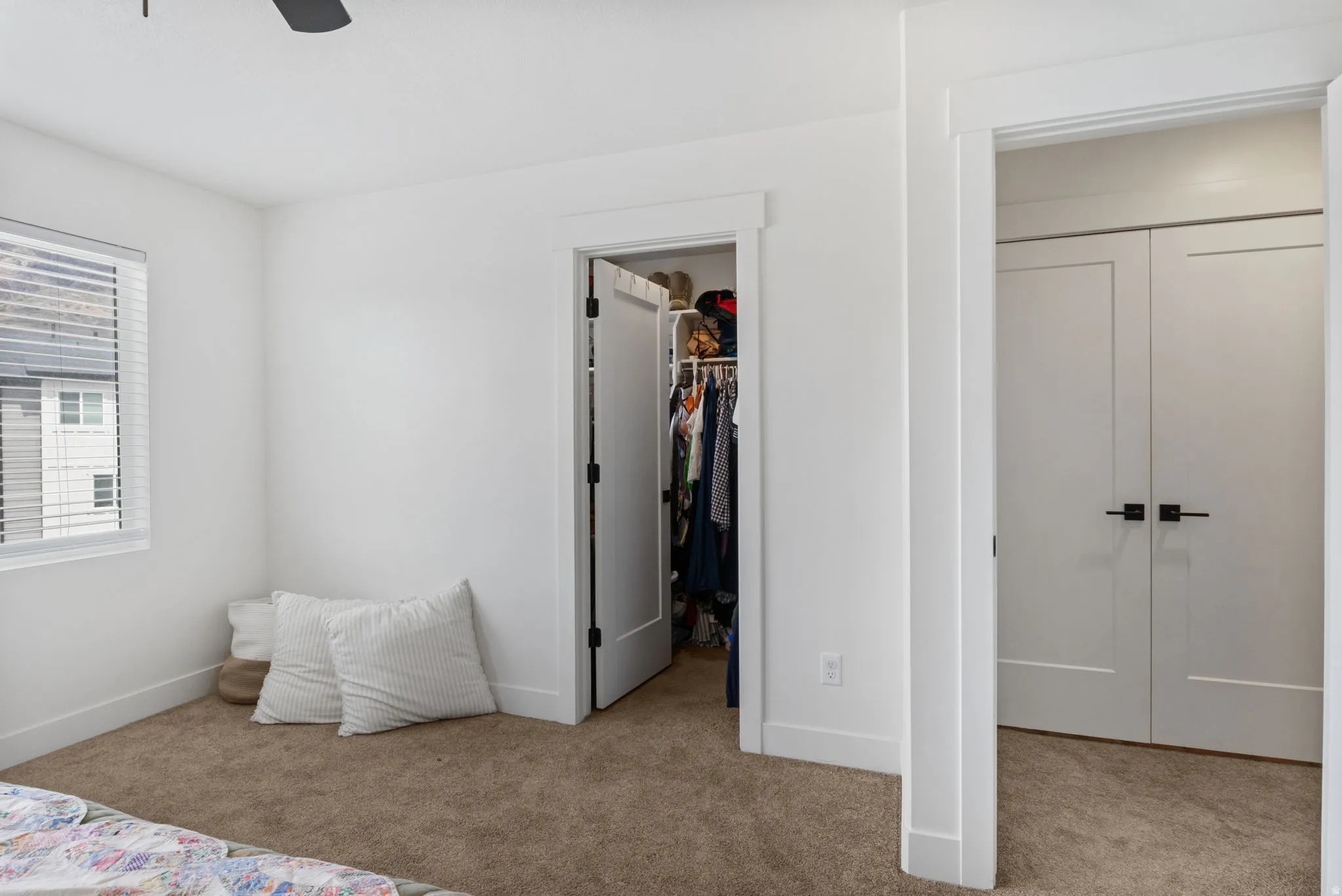 Neutral wall finishes, textured carpet flooring, white window blinds, and recessed closet access with modern hardware