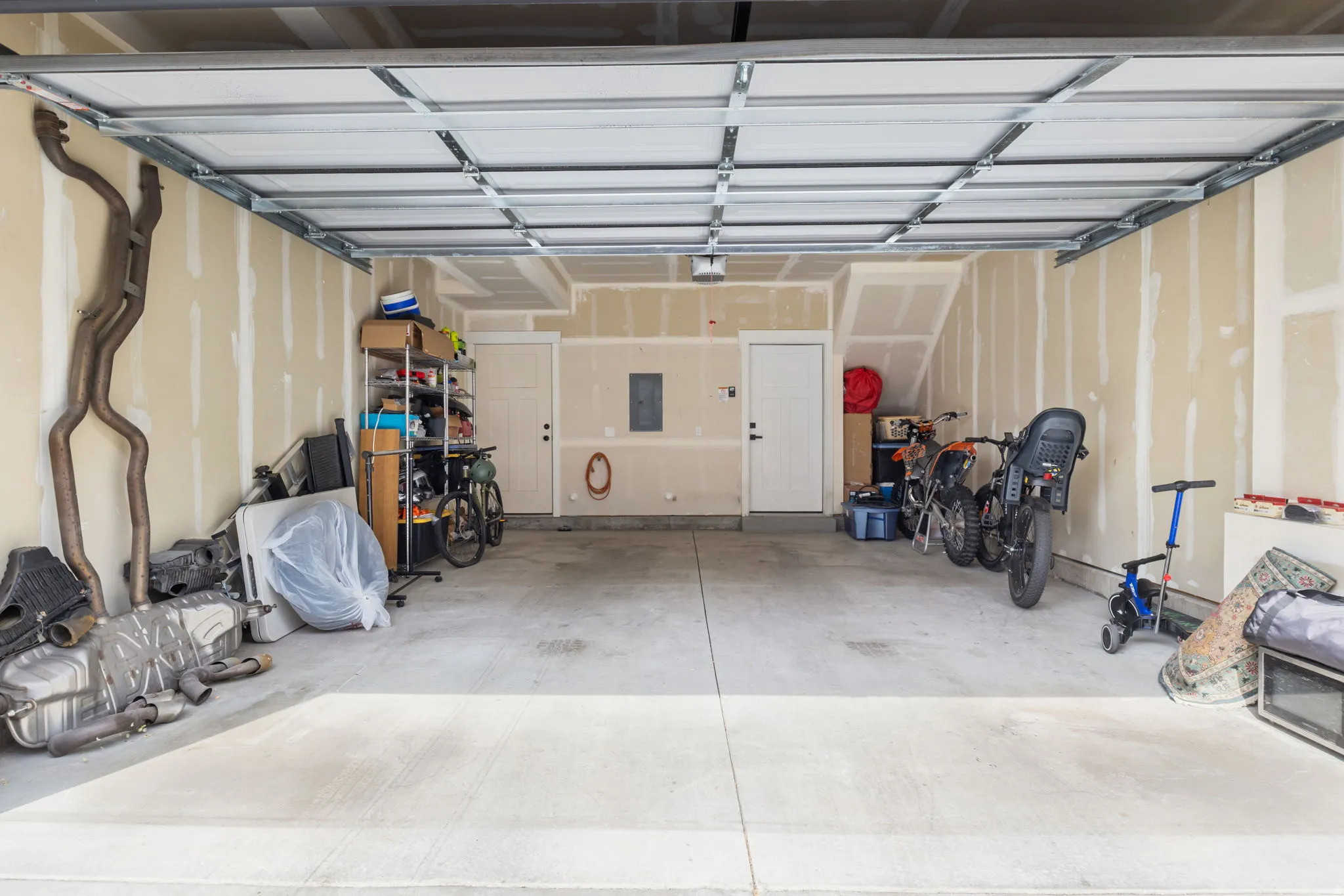 Concrete floor attached garage with white panel door leading to first floor entry
