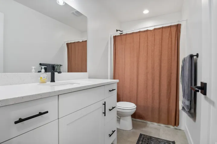 White cabinetry with matte black hardware, integrated sink, and a speckled white countertop