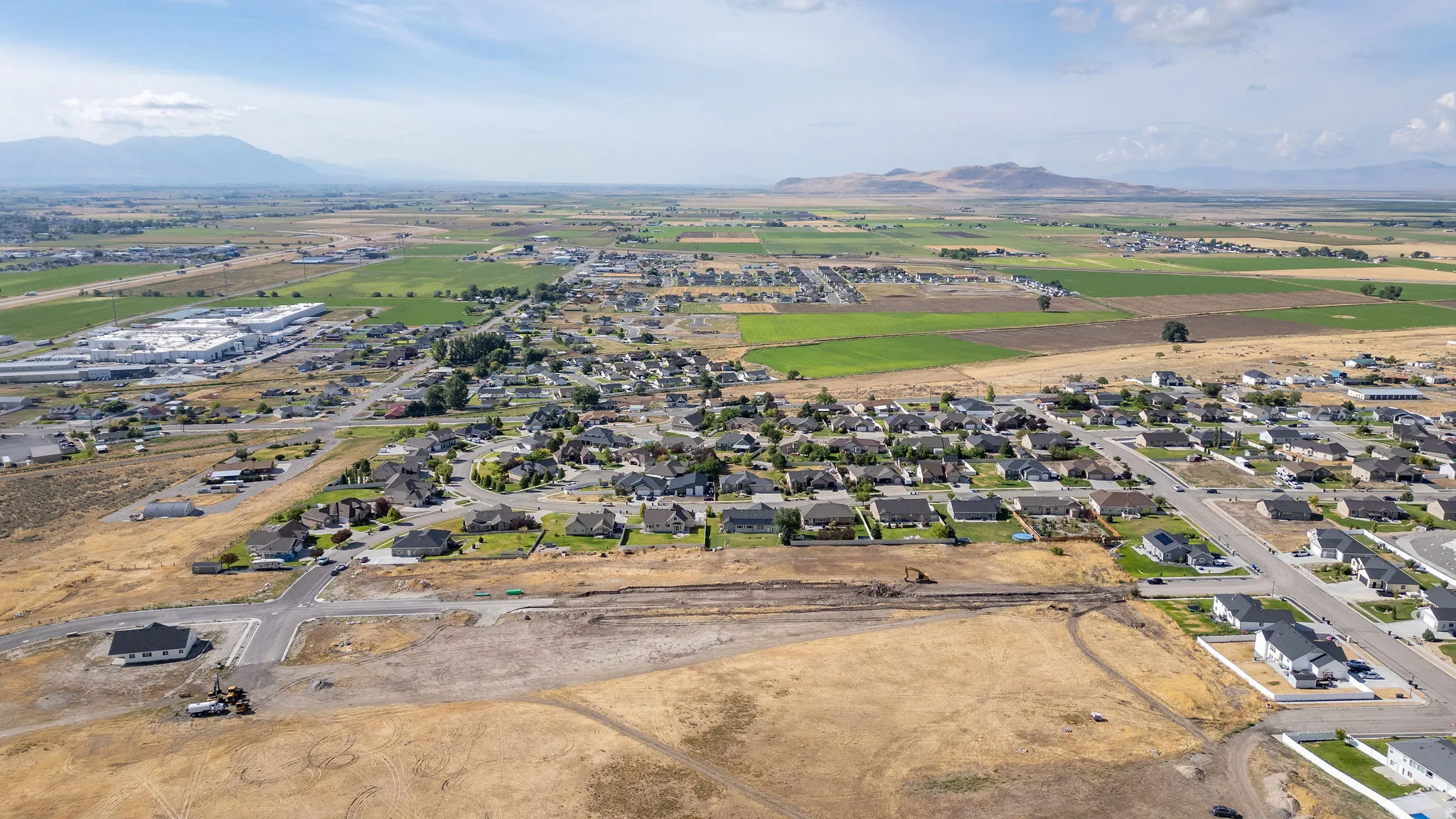 Expansive undeveloped land with surrounding residential areas and distant mountains