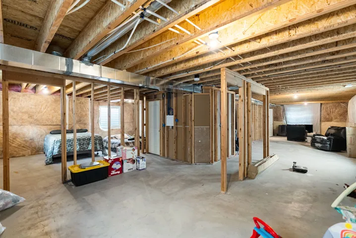 Unfinished lower level with exposed ceiling joists, concrete flooring, and partial wall framing