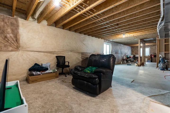 Expansive unfinished basement featuring concrete flooring, exposed ceiling joists, and insulated walls