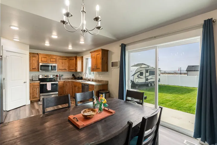 Kitchen and dining area featuring wood-finish cabinetry, stainless steel appliances, and a chandelier